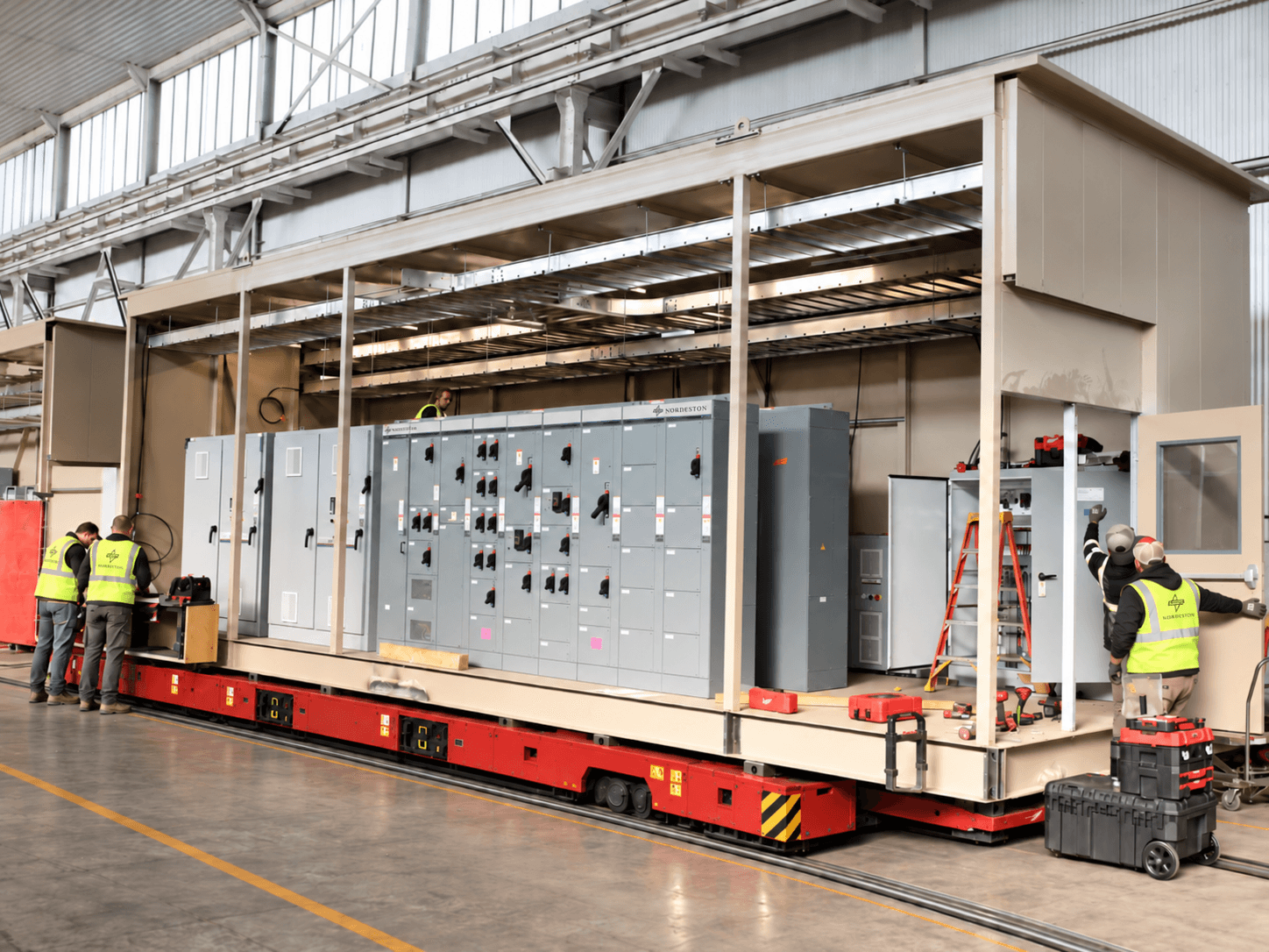 Modular Nordeston PowerPlatform E-House undergoing factory assembly and electrical integration on a rail-mounted production platform.