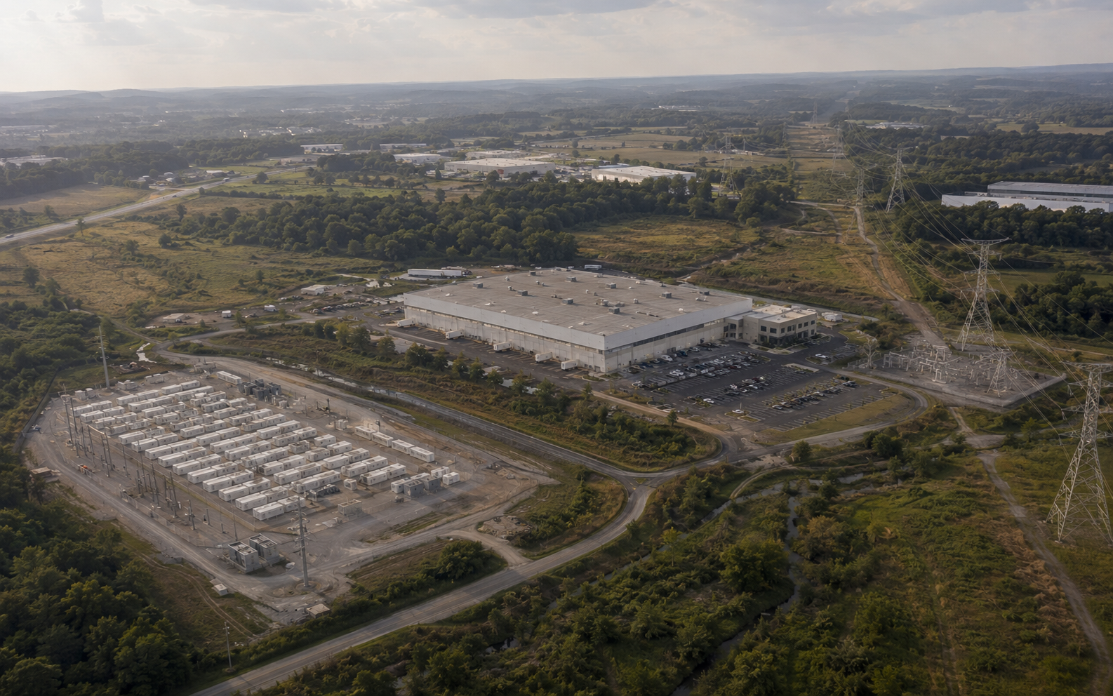 Aerial view of industrial infrastructure corridor combining battery storage, manufacturing, and transmission